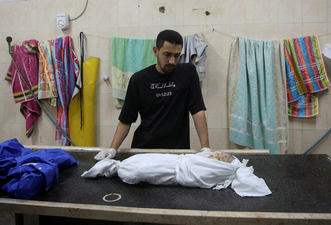 A Palestinian man watches over the body of a child who was killed in Israeli strikes in Rafah, southern Gaza Strip, on April 27, 2024. (REUTERS)