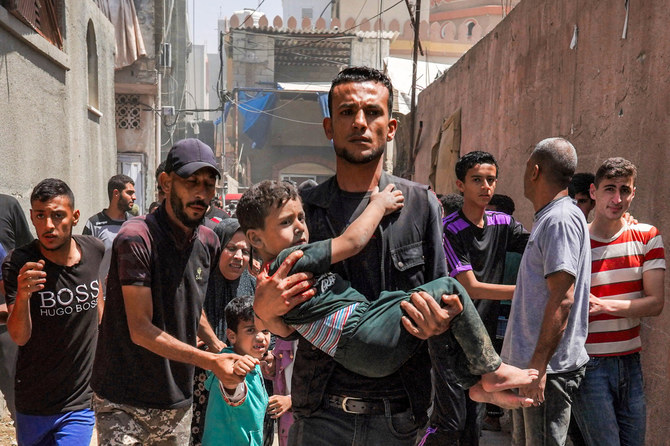 A man carries a child as he walks with other people fleeing following Israeli bombardment in Nuseirat in the central Gaza Strip amid the ongoing conflict in the Palestinian territory between Israel and the militant group Hamas. (File/AFP)