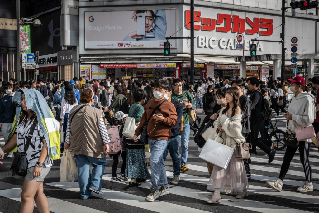People cross a street in Shinjuku area of Tokyo on March 30, 2024. (AFP)