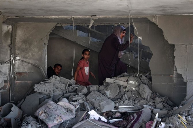 A Palestinian woman and children check the rubble of a building hit by overnight Israeli bombing in Rafah in the southern Gaza Strip on Apr. 20, 2024. (AFP)