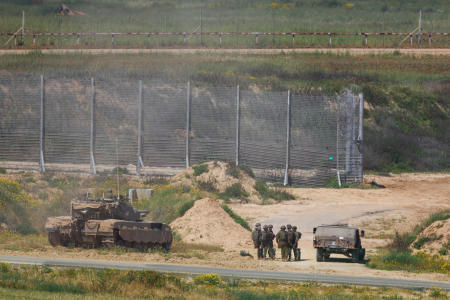 Israeli soldiers stand near military vehicles, amid the ongoing conflict between Israel and the Palestinian Islamist group Hamas, near the Israel-Gaza border, as seen from Israel, April 4, 2024. (Reuters)
