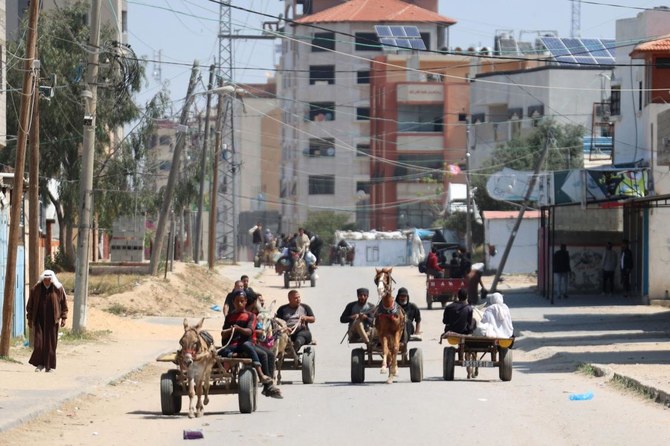 Palestinians transport belongings as people fleeing conflict leave their homes, in the Nuseirat refugee camp in central Gaza on Apr. 12, 2024. (AFP)