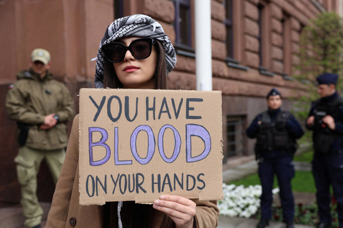 A demonstrator holds a placard in front of the Polish foreign ministry in Warsaw to protest the death of Polish aid worker Damian Sobol by the Israeli army in Gaza on April 5, 2023. (Agencja Wyborcza.pl via Reuters)