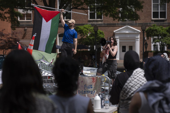 People stand atop a pile of barricades as they lead a chant at an encampment by students protesting against the Israel-Hamas war at George Washington University in Washington. (File/AP)