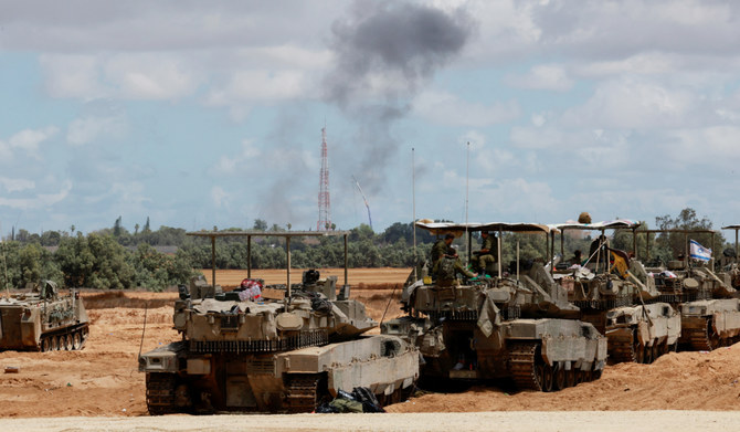 Israeli soldiers sit on tanks as smoke billows in the distance, amid the ongoing conflict between Israel and the Palestinian Islamist group Hamas, near the Israel-Gaza Border, in Israel, May 6, 2024. (REUTERS)