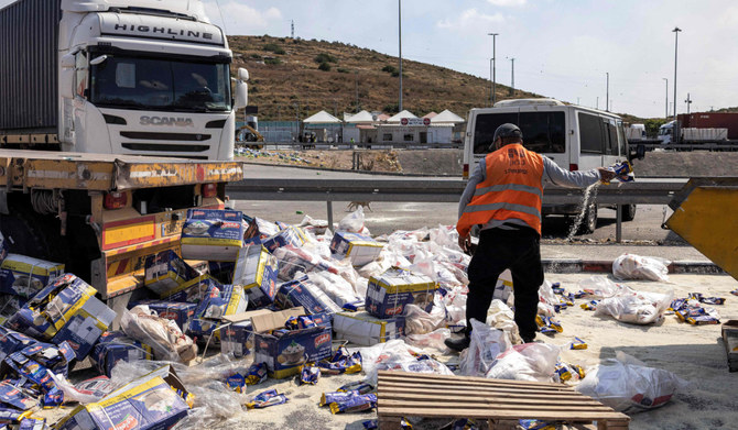A worker clears spilled goods away from damaged trailer trucks that were carrying humanitarian aid supplies on the Israeli side of the Tarqumiyah crossing with the occupied West Bank on May 13, 2024, after they were vandalised by other activists to protest against aid being sent to the Gaza Strip. (AFP)