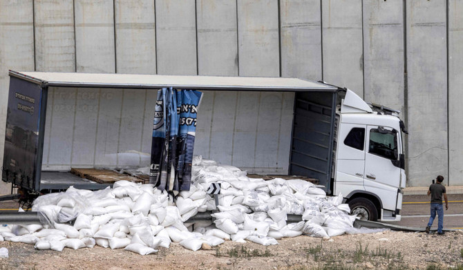 A man films with his phone a damaged trailer truck that was carrying humanitarian aid supplies parked along the Israeli side of Israel's controversial separation barrier with the West Bank near the village of Shekef on May 13, 2024, after it was vandalised by right-wing Israeli activists to protest against aid being sent to the Gaza Strip. (AFP)