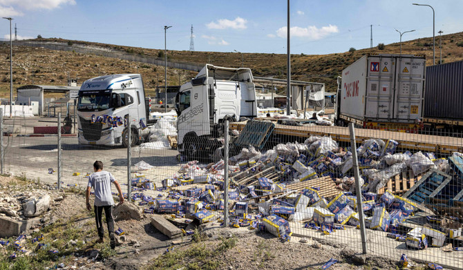 A youth walks near the damaged trailer trucks that were carrying humanitarian aid supplies on the Israeli side of the Tarqumiyah crossing with the occupied West Bank on May 13, 2024, after they were vandalised by right-wing Israeli activists to protest against aid being sent to the Gaza Strip. (AFP)