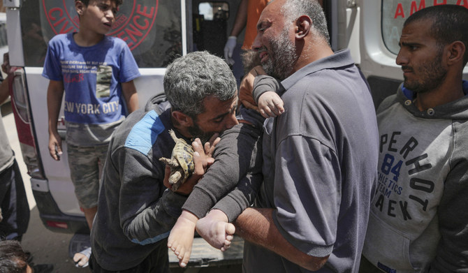 Palestinians hold the body of a dead baby rescued from the rubble of a building destroyed in an Israeli airstrike in Nuseirat, Gaza Strip, Tuesday, May 14, 2024. (AP)