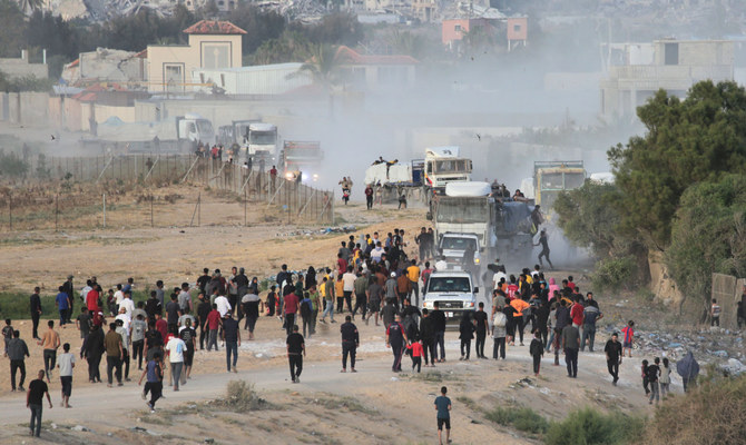 Palestinians rush trucks as they transport international humanitarian aid from the US-built Trident Pier near Nuseirat in the central Gaza Strip on May 18, 2024, amid the ongoing conflict between Israel and the militant group Hamas. (AFP)
