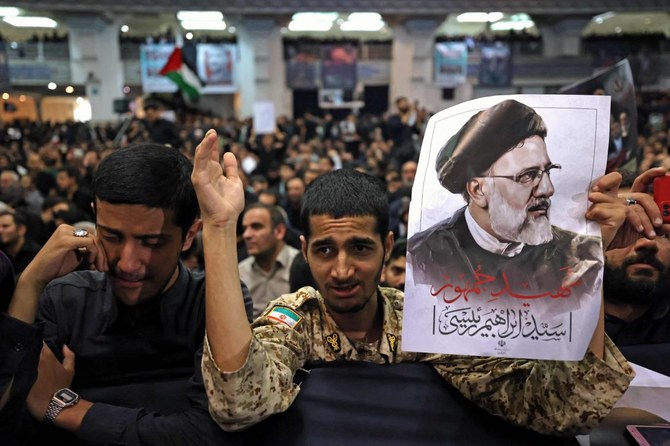 A mourner holds a poster of late Iranian President Ebrahim Raisi during a funeral ceremony for him and his companions who were killed in a helicopter crash at Mosalia mosque in Tehran, on May 21, 2024. (AFP)