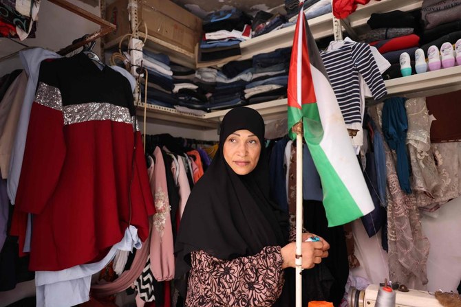 A shop owner carries a Palestinian flag in her store in the Palestinian refugee camp of Shatila in Beirut’s southern suburb on May 22, 2024. (AFP)