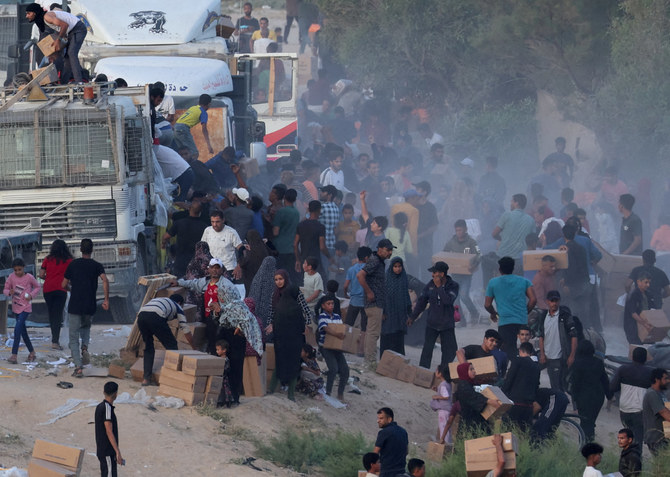 Palestinians climb onto trucks to grab aid that was delivered into Gaza through a US-built pier, as seen from central Gaza Strip, on May 18, 2024. (REUTERS)