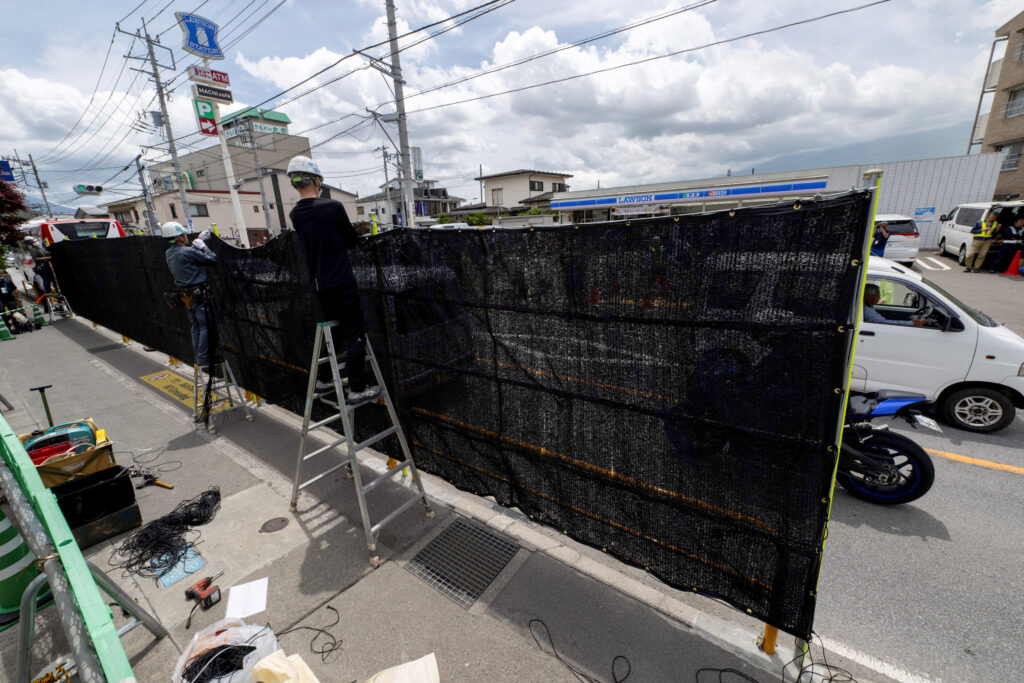 Workers install a barrier to block the sight of Japan's Mount Fuji emerging from behind a convenience store to deter badly behaved tourists, in the town of Fujikawaguchiko, Yamanashi prefecture on May 21, 2024. (AFP)