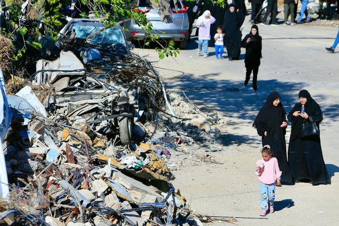 Women walk past the rubble of a building destroyed by Israeli bombardment after attending the funeral of a Hezbollah militant killed in an Israeli strike in the southern Lebanese village of Meis Al-Jabal. (AFP)