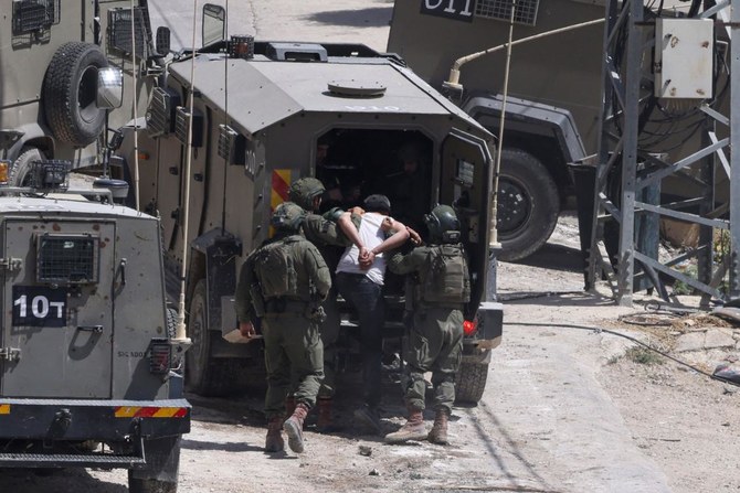 Israeli soldiers detain a Palestinian man during a raid in the occupied West Bank town of Deir Al-Ghusun near Tulkarem on May 4, 2024. (AFP)