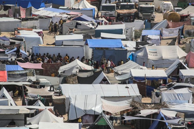 Palestinians line up to receive humanitarian aid amidst tents housing internally displaced people, along the coastline in Deir el-Balah in the central Gaza Strip on May 10, 2024, amid the ongoing conflict between Israel and the militant group Hamas. (AFP)