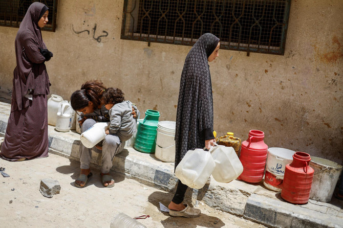 Palestinians wait to collect water in Khan Younis, in the southern Gaza Strip, on May 22, 2024. (Reuters)