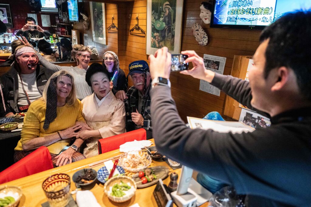 Behind the bar, dressed in a smart pale kimono with her hair in a traditional up-do, is 