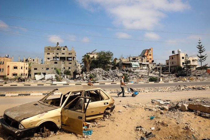 Palestinian men walk past damaged buildings after an overnight Israeli strike in Al-Bureij camp in the central Gaza Strip on Jun. 3, 2024. (AFP)