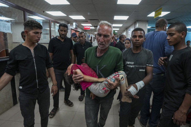 A Palestinian man brings a child wounded in the Israeli bombardment of the Gaza Strip into a hospital in Deir al Ballah on June 5, 2024. (AP)