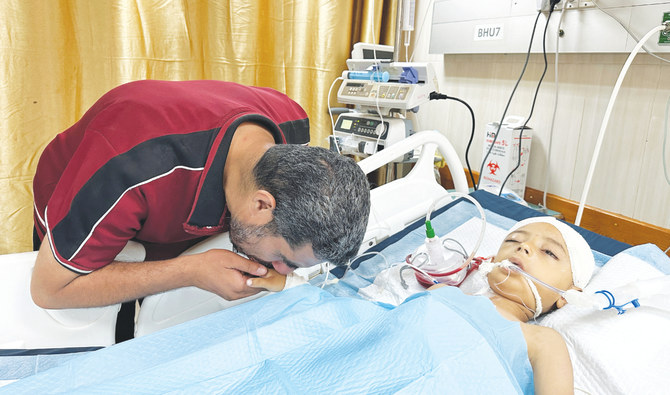 A father kisses the hand of his injured child, Tawfik Abu Youssef, on Sunday at Al-Aqsa Martyrs Hospital in Deir Al-Balah, central Gaza Strip. (Reuters)