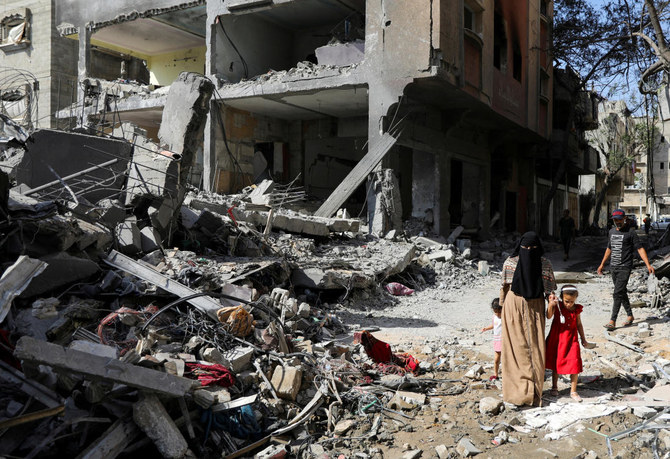 A woman and child walk among debris, aftermath of Israeli strikes at the area, where Israeli hostages were rescued on Saturday, as Palestinian death toll rises to 274, amid the Israel-Hamas conflict, in Nuseirat refugee camp in the central Gaza Strip, June 9, 2024. (Reuters)