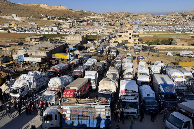 Syrian refugees gather near trucks with their belongings, as they prepare to go back home to Syria as a part of a voluntary return, in the eastern Lebanese border town of Arsal, Tuesday, May 14, 2024. For more than a decade, a steady flow of Syrians have crossed the border from their war-torn country into Lebanon. But anti-refugee sentiment is rising there, and over the past two months, hundreds of Syrian refugees have gone the other way. (AP Photo/Hussein Malla, File)