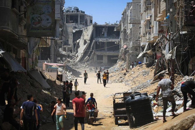 Palestinian citizens walk past buildings destroyed in the Israeli bombardment of Khan Yunis, in the southern Gaza Strip amid the ongoing conflict between Israel and the Palestinian Hamas militant group. (File/AFP)