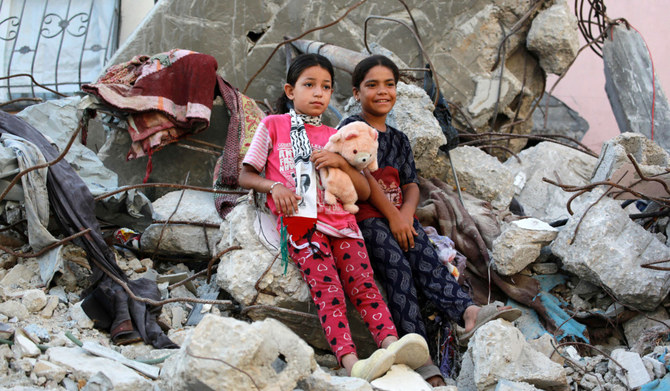 Palestinian girls — dressed in new clothes — lean against the rubble of a destroyed building as they celebrate Eid Al-Adha in Khan Younis. (AFP)