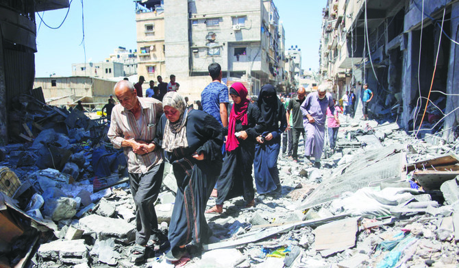 People make their way through the rubble of buildings destroyed during Israeli bombardment at Al-Shati refugee camp in Gaza City on Saturday. (AFP)