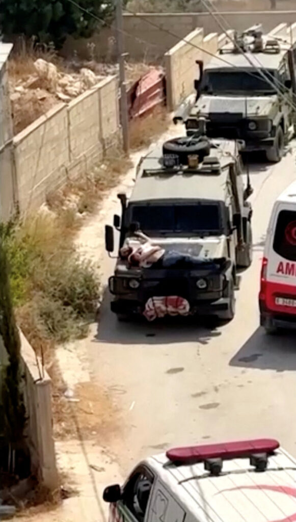 Israeli army straps Palestinian on military jeep during raid in Jenin, in this screengrab from a video, in the Israeli-occupied West Bank, June 22, 2024. (Reuters)