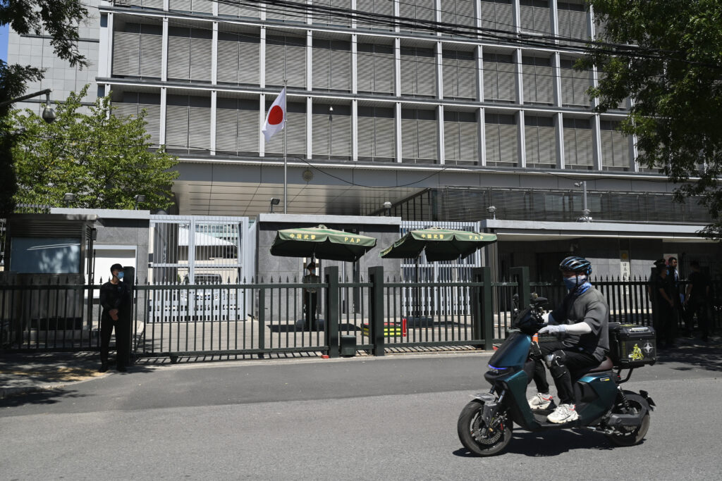 A man rides his motorcycle past the entrance of the Japanese embassy in Beijing on August 29, 2023. (AFP)