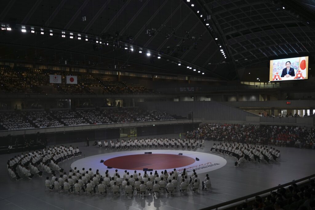 TEAM JAPAN, athletes and staff representing Japan in the upcoming Paris 2024 Olympic Games, watch a video message from Japan's Prime Minister Fukio Kishida, right on screen, during a send-off ceremony for the Paris Olympics Friday, July 5, 2024, in Tokyo. (AP)