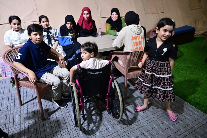 An injured young Palestinian evacuated from the Gaza Strip is surrounded by patients and family members as he sits in a wheelchair aboard an Emirati floating hospital in the Egyptian port of Al-Arish on Jul. 4, 2024. (AFP)