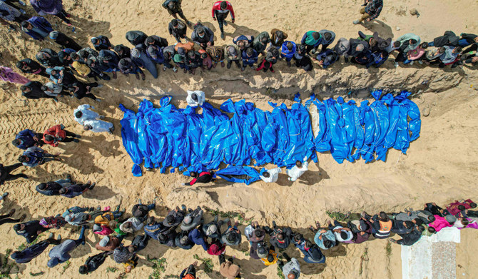 An aerial view shows mourners watching as medical personnel prepare the bodies of 47 Palestinians, that were taken and later released by Israel, during a mass funeral in Rafah in the southern Gaza Strip on March 7, 2024, amid ongoing battles between Israel and the militant group Hamas. (AFP)