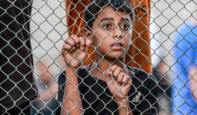A boy reacts as he stands with others behind a fence as the bodies of victims killed in Israeli bombardment and survivors arrive at the Nasser Medical Complex in Khan Yunis in the southern Gaza Strip on July 5, 2024 amid the ongoing conflict in the Palestinian territory between Israel and Hamas. (AFP)