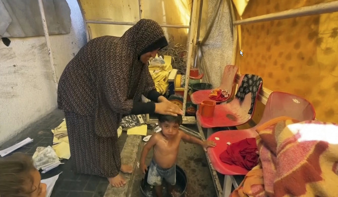 This image from video shows a woman bathing her child Friday, July 5, 2024 in Gaza City, Gaza. (AP)