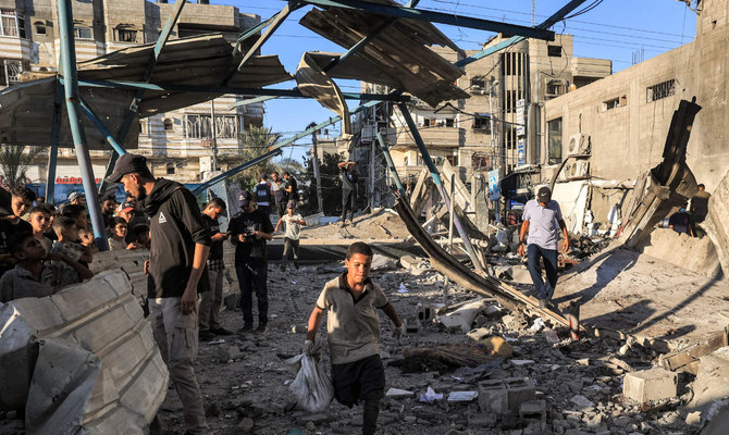 A boy runs with a sack as people search the rubble of a collapsed building in the aftermath of Israeli bombardment at the Jaouni school run by the UN Relief and Works Agency for Palestine Refugees (UNRWA) in Nuseirat in the central Gaza Strip on July 6, 2024 amid the ongoing conflict in the Palestinian territory between Israel and Hamas. (AFP)
