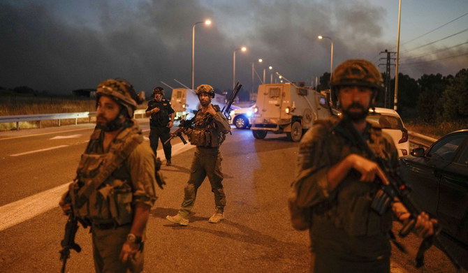 Israeli soldiers block a road backdropped by smoke from a fire after a rocket fired from Lebanon hit in the Israeli-annexed Golan Heights, Tuesday, July 9, 2024. (AP)