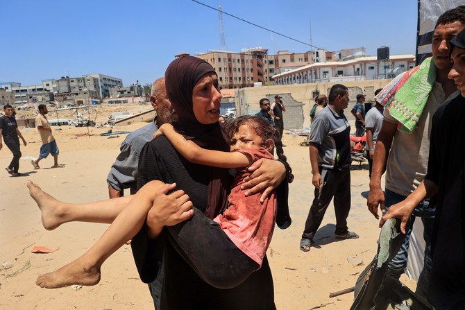 A Palestinian woman carries an injured child to the Nasser hospital in Khan Yunis on July 13, 2024, one of the health establishments to which casualties were rushed after an Israeli strike killed at least 90 people and injured many others at the Al-Mawasi camp for the war displaced in the south of the Palestinian territory, according to the Hamas-run health ministry. (AFP)