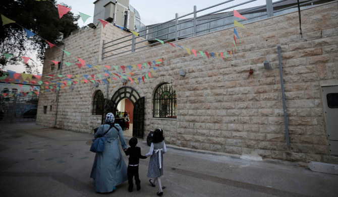 A Palestinian mother and her children walk on October 28, 2014, outside the Palestinian national theatre, also known as al-Hakawati theatre in east Jerusalem. (AFP)