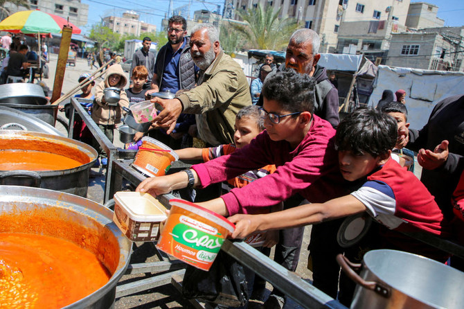 Palestinians gather to receive food cooked by a charity kitchen, amid shortages of aid supplies, after Israeli forces launched a ground and air operation in the eastern part of Rafah. (Reuters)