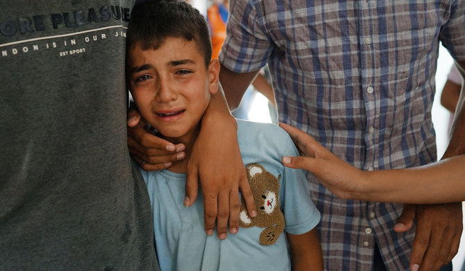 Palestinian Civil Defence members and relatives comfort eleven-yaer-old Ahmed -- the son of their colleague Bilal Ramadan Farhan, 42, who died of injuries sustained in Israeli bombing of al-Mawasi area two days earlier -- during his funeral at Nasser hospital in Khan Yunis on July 15, 2024, amid the continuing conflict between Israel and the Palestinian Hamas militant group. (AFP)
