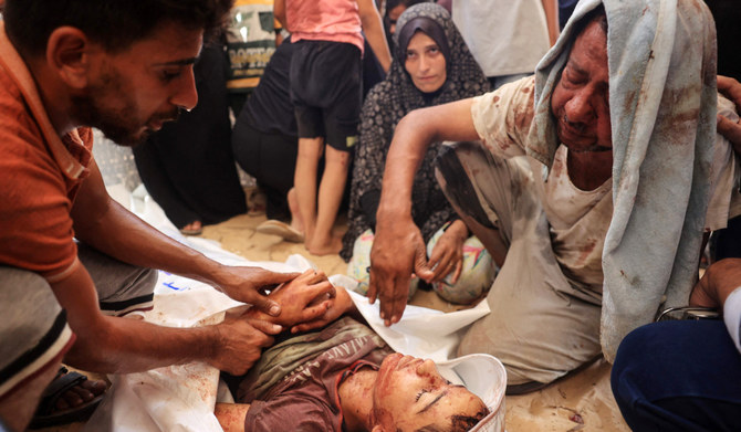 Palestinians surround the corpse of a child in front of the morgue of the Nasser hospital in Khan Yunis on July 13, 2024, one of the health establishments to which casualties were rushed after an Israeli strike killed at least 71 people at the Al-Mawasi camp for the war displaced in the south of the Palestinian territory, according to the Hamas-run health ministry. (AFP)