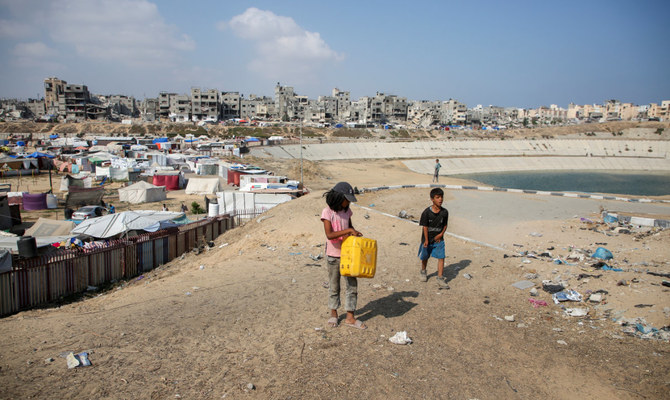 Palestinian children walk near a wastewater pool as displaced Palestinians shelter in a tent camp, amid the Israel-Hamas conflict, in Khan Younis in the southern Gaza Strip, July 15, 2024. (Reuters)