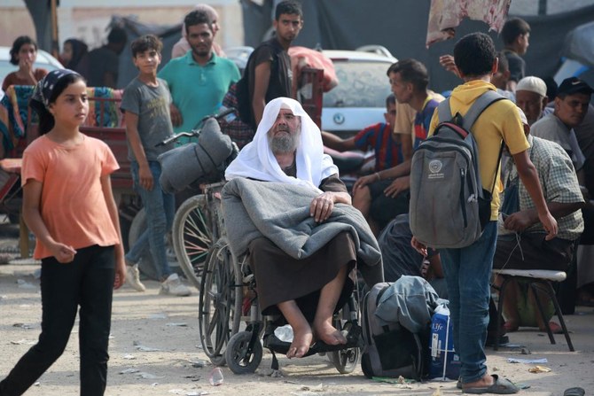 A Palestinian man sits in his wheechair next to his bag, as thousands of Palestinians who fled following the Israeli army’s temporary evacuation order for parts of Khan Yunis, arrive in an another area of the southern Gaza Strip city on July 23, 2024. (AFP)