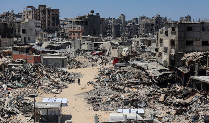 People walk on a street next to buildings destroyed during Israeli bombardment at the Jabalia camp for Palestinian refugees in the northern Gaza Strip on July 23, 2024. (AFP/File)