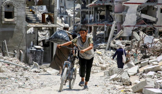 A Palestinian pushes a bicycle as he walks past the rubble of houses destroyed during the Israeli military offensive, amid Israel-Hamas conflict, in Khan Younis in the southern Gaza Strip July 10, 2024. (REUTERS)