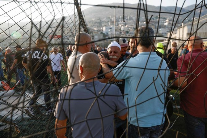 Local residents comfort each other as they gather at a site where a reported strike from Lebanon fell in Majdal Shams village in the Israeli-annexed Golan area on July 27, 2024. (AFP)
